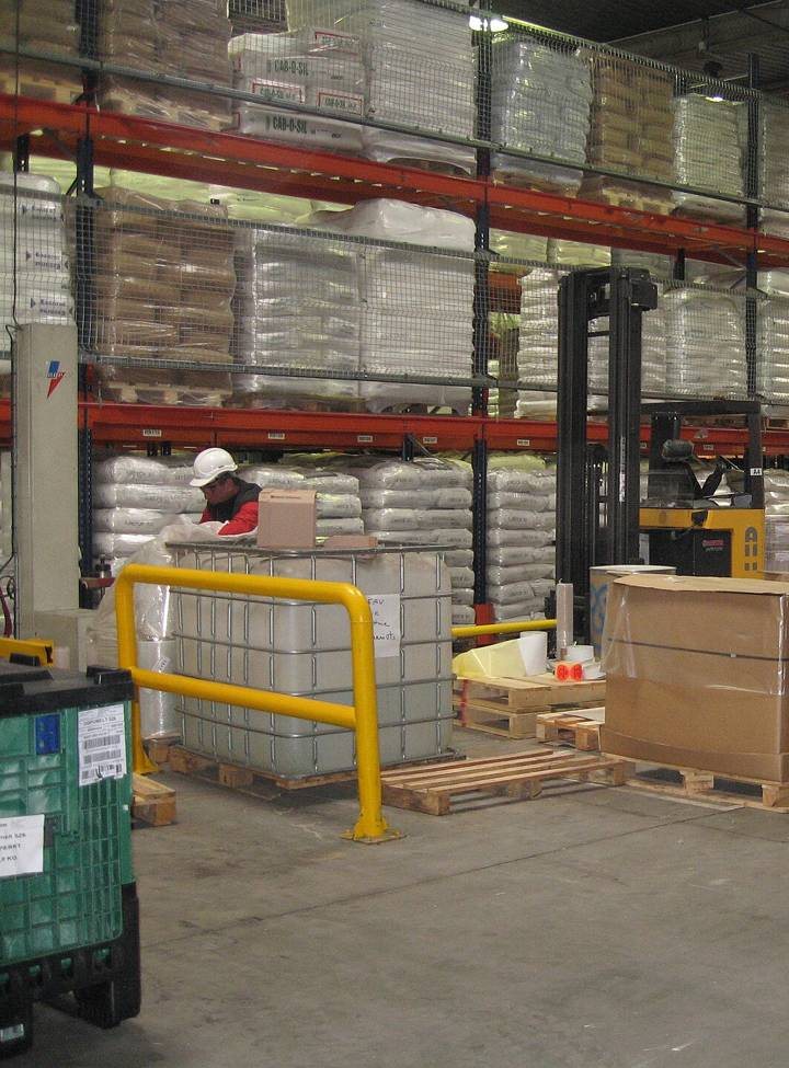 A worker in a hard hat beside pallet racking with red beams