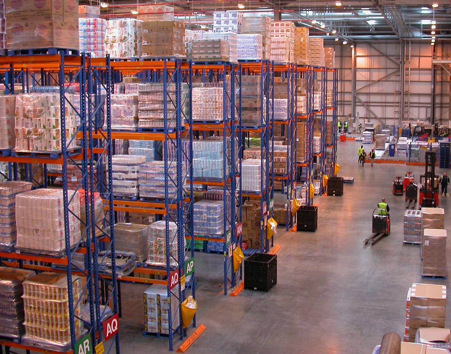 Blue uprights and orange beams of pallet racking in a busy distribution centre